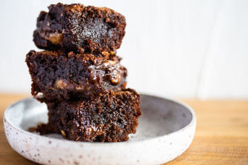 Chocolate brownie on a white plate and wood surface