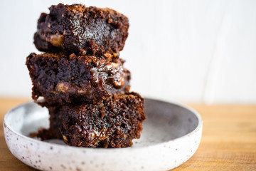 Chocolate brownie on a white plate and wood surface