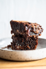 Chocolate brownie on a white plate and wood surface