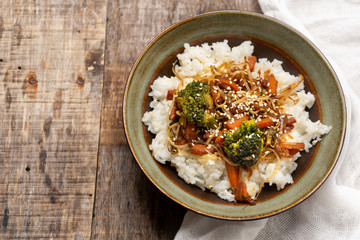 Thai style rice with fried vegetables and soy sauce on wooden background