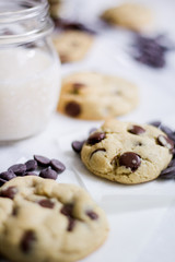 Chocolate chip cookie with vanilla dough on an white surface with glass of milk