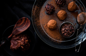 Date energy ball with cocoa on a black dish and cocoa nibs