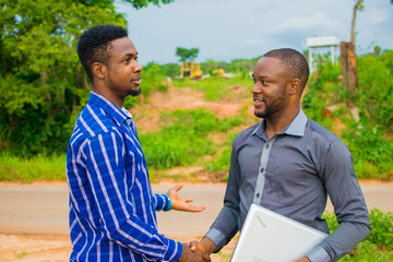 two young african businessmen exchanging handshakes over a done deal.