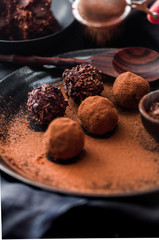 Date energy ball with cocoa on a black dish and cocoa nibs