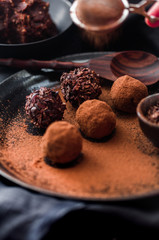 Date energy ball with cocoa on a black dish and cocoa nibs