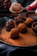 Date energy ball with cocoa on a black dish and cocoa nibs