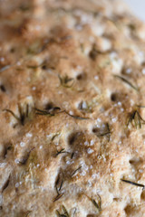 rosemary focaccia on a white surface and yellow kitchen towel