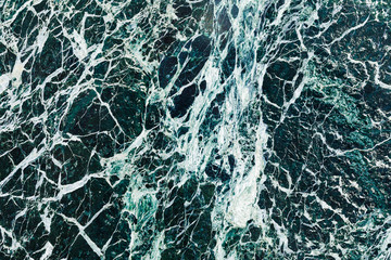 Dark green abstract texture with white streaks similar to ice with cracks. Material for finishing and construction.