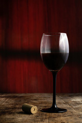 copa de vino tinto sobe mesa rustica de madera y fondo rojo