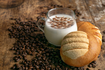 copa de leche sobre mesa de madera rustica con granos de cafe cocoa y pan