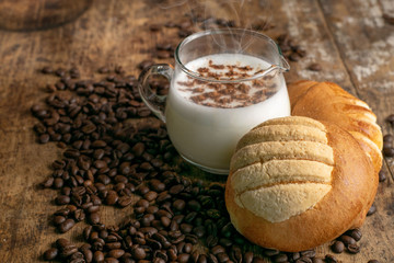 copa de leche sobre mesa de madera rustica con granos de cafe cocoa y pan