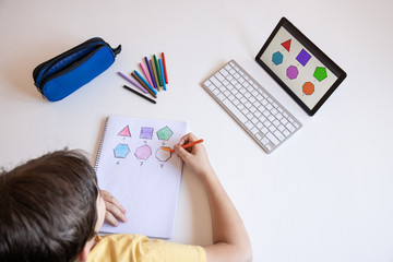 Student boy performs his academic tasks and learns from home