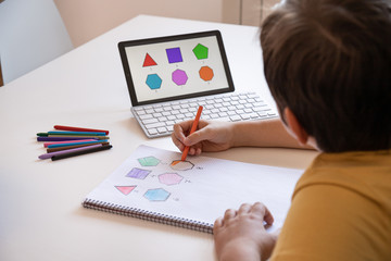 Student boy performs his academic tasks and learns from home