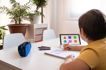 Student boy performs his academic tasks and learns from home
