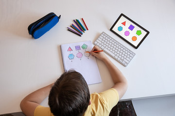 Student boy performs his academic tasks and learns from home