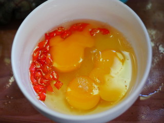 Raw egg and red chilies slice in a bowl. Prepare to make an omelette.
