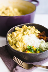 Curry chicken with chutney  on a gray ceramic and several side dish