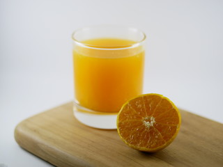 Fresh orange juice in glass cup next to a sliced orange