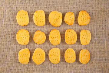 Delicious gluten-free homemade cookies lie in even rows on burlap. Top view