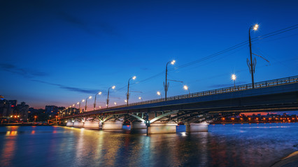 Beautiful panoramic view at illuminated Voronezh city bridge in blue hour after sunset.