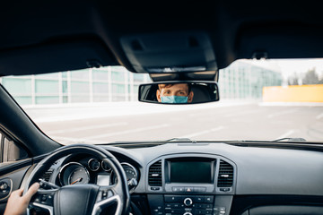 Obraz premium A man in a protective medical mask, sitting behind the wheel of a car. Quarantine, coronavirus