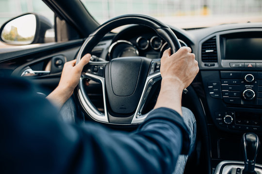 hands of a man holding the steering wheel while driving a car
