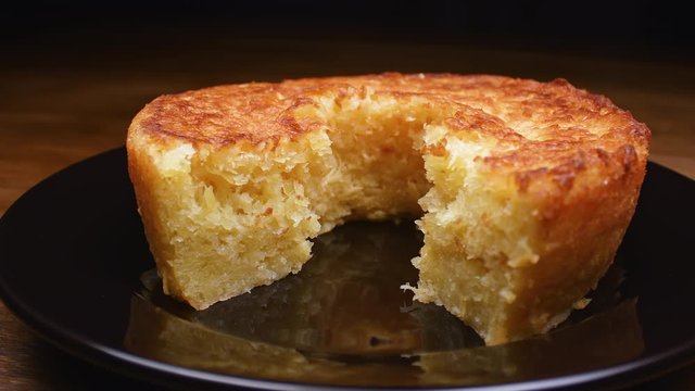 Cassava cake with a cut piece and cassava in the background