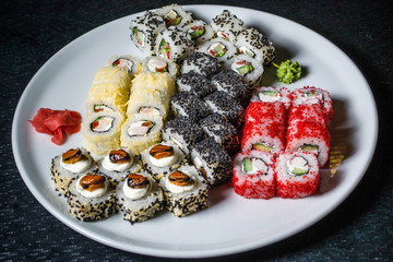 Set of different rolls on a white plate against a dark background