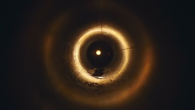 A bright orange flash of fire with sparks inside a metal pipe illuminates the space inside with radial reflections. Closeup. Slow motion. High speed camera. V-log - High Dynamic Range