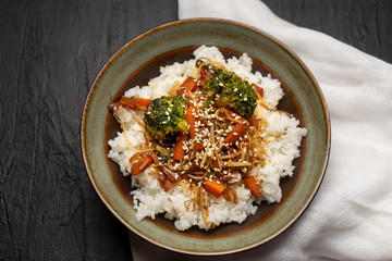 Thai style rice with fried vegetables and soy sauce on dark background