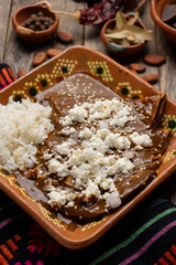 Mexican mole enchiladas with rice on wooden background