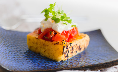 grilled polenta with tomato sauce and cheese and sprouts