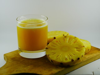 juice and slices of pineapple on wooden board