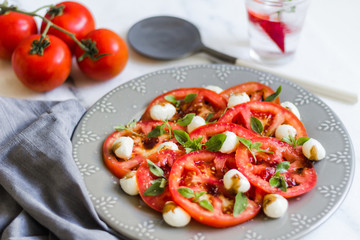 Homemade Caprese Salad on a white surface and gray dish with a rustic napkin