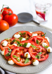Homemade Caprese Salad on a white surface and gray dish with a rustic napkin