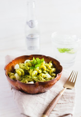 Homemade pasta salad with pesto and buffalo mozzarella on a white surface and rustic napkin