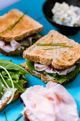 turkey breast sandwich with arugula and blue cheese on a blue surface