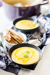 Creamy soup with toast on a white surface