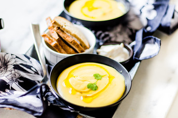 Creamy soup with toast on a white surface