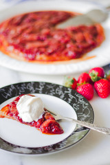 Strawberries tarte tatin with cream on a slice being served