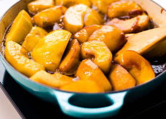 Apple caramelized in a cast iron pan with blue handle and blue spatula