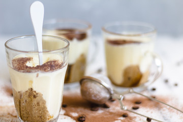 Tiramisu in a glass with cocoa powder on a marble and gray background