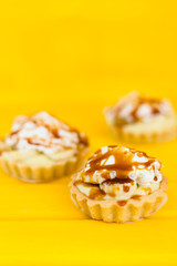 Banana pie with cream and caramel on a yellow background