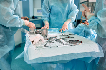Sterile instruments on the operating table, a team of doctors lays out the instruments for the operation. many hands are brewing in sterile gloves.
