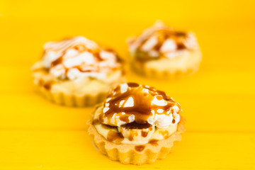 Banana pie with cream and caramel on a yellow background