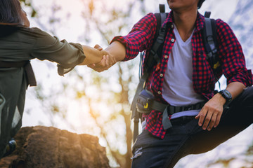 Close up of Couple hiking help each other hike up a mountain. Help and support concept. - obrazy, fototapety, plakaty