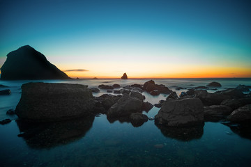 Stones in the water of the Pacific Ocean, with rocks in the water at sunset. Night landscape