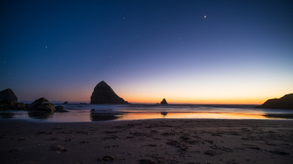 Night landscape of pacific ocean beach in USA, cliffs, and night stars. Beautiful sunset