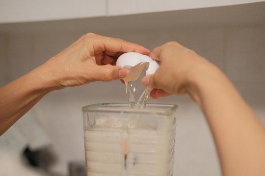 Abriendo o quebrando huevo sobre licuadora mientras cae la clara para realizar mezcla de pastel.