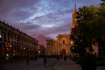 Obraz premium The view of Plaza de Armas, historical center of Arequipa with the Cathedral and stunning purple clouds and sunset mountains in the back 